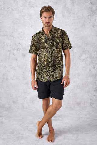 Man wearing a patterned shirt and black shorts on a gray background